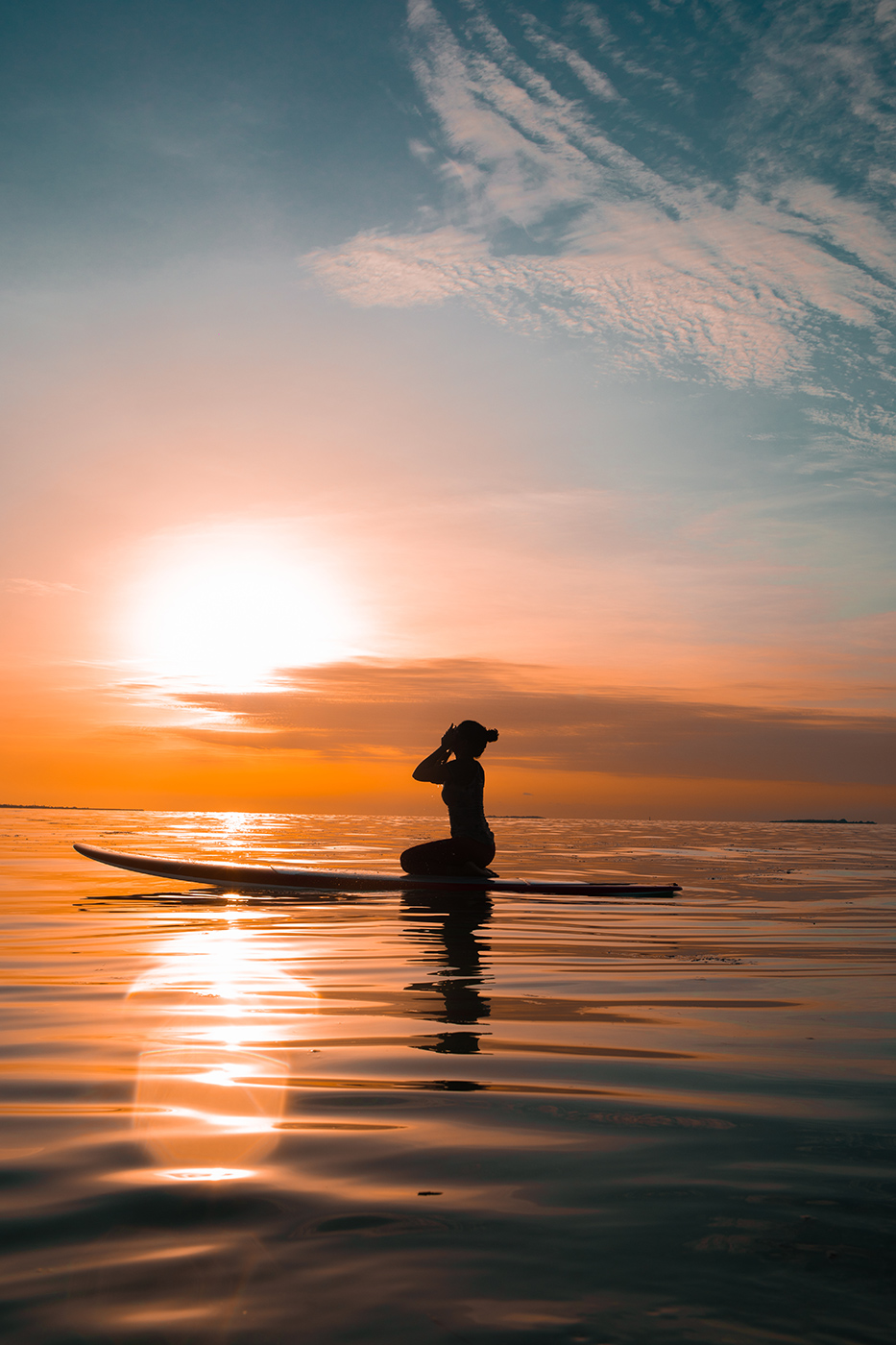 Frau auf Paddleboard bei Sonnenuntergang