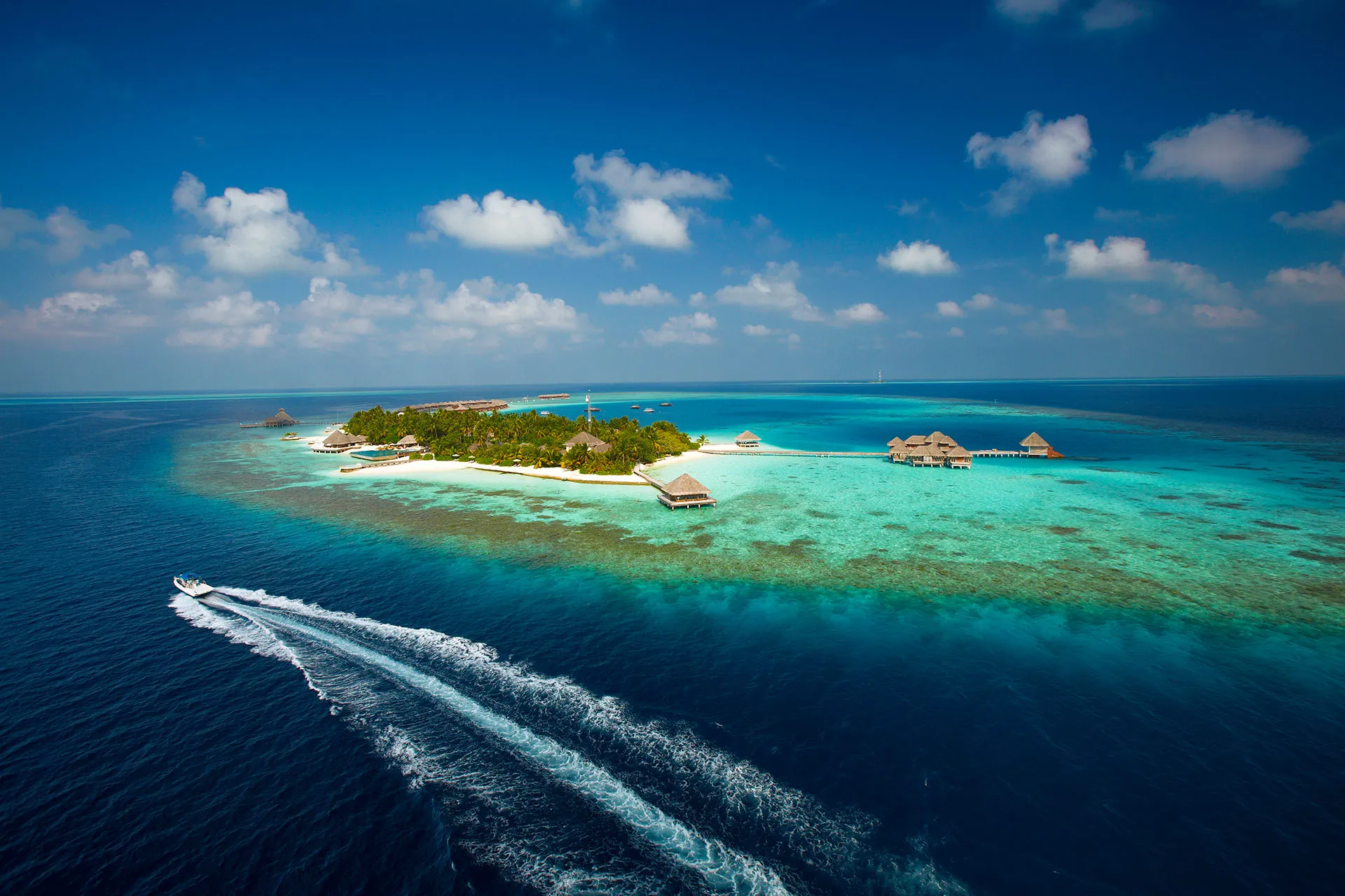Speedboot fährt an maledivischer Insel vorbei