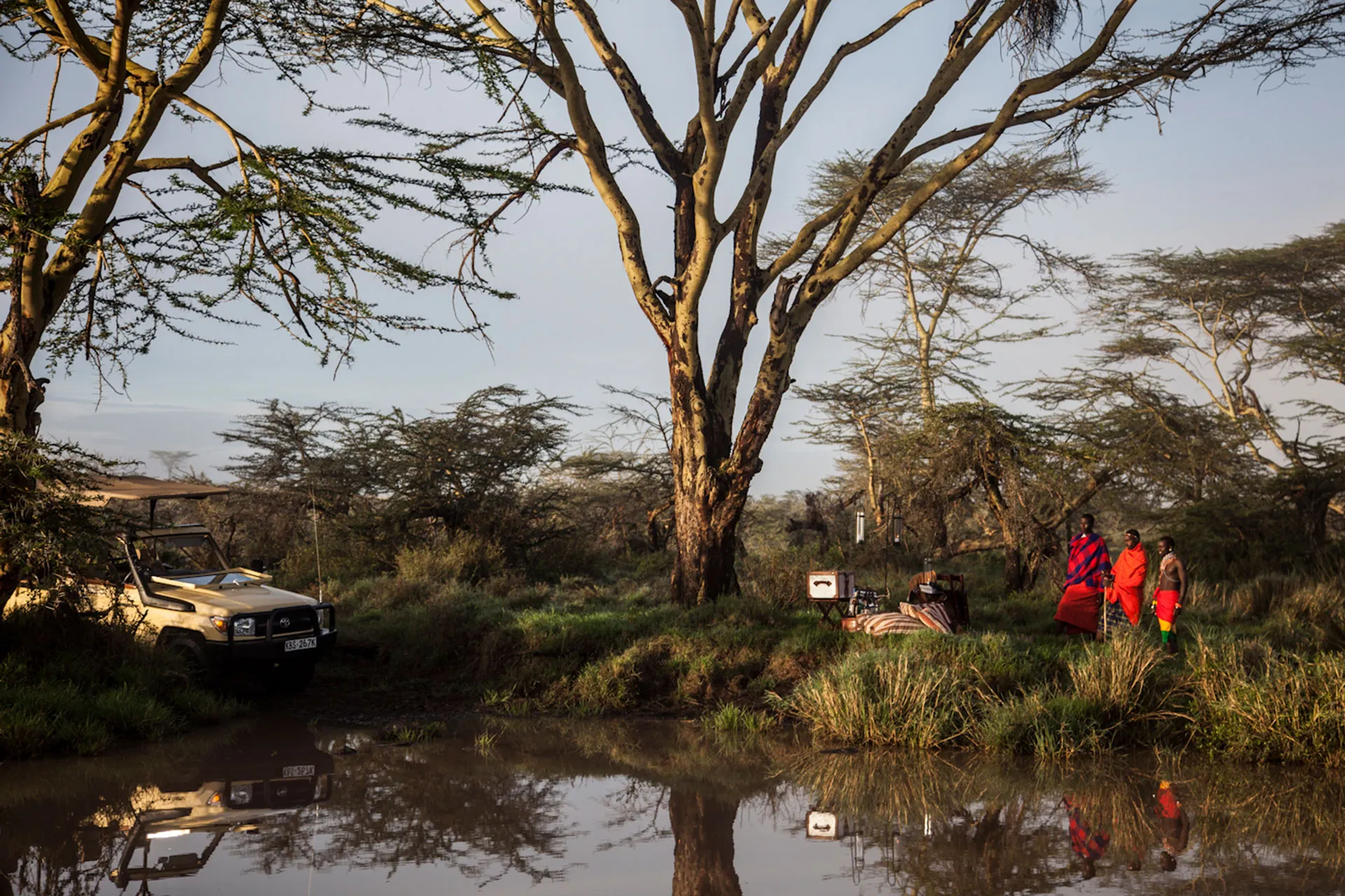 Drei Massai an Wasserstelle in Afrika