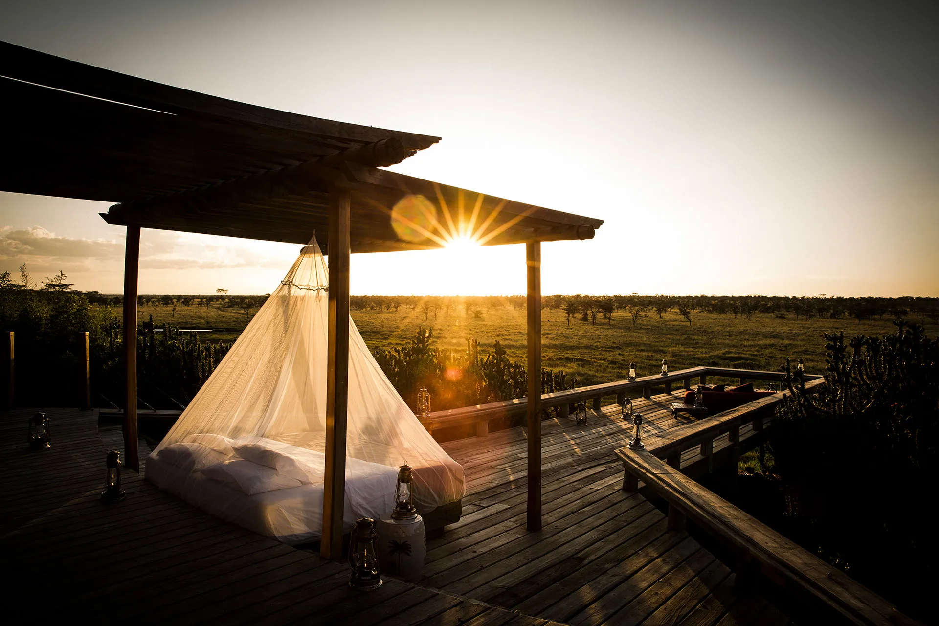 Bett auf Holzterrasse bei Sonnenuntergang