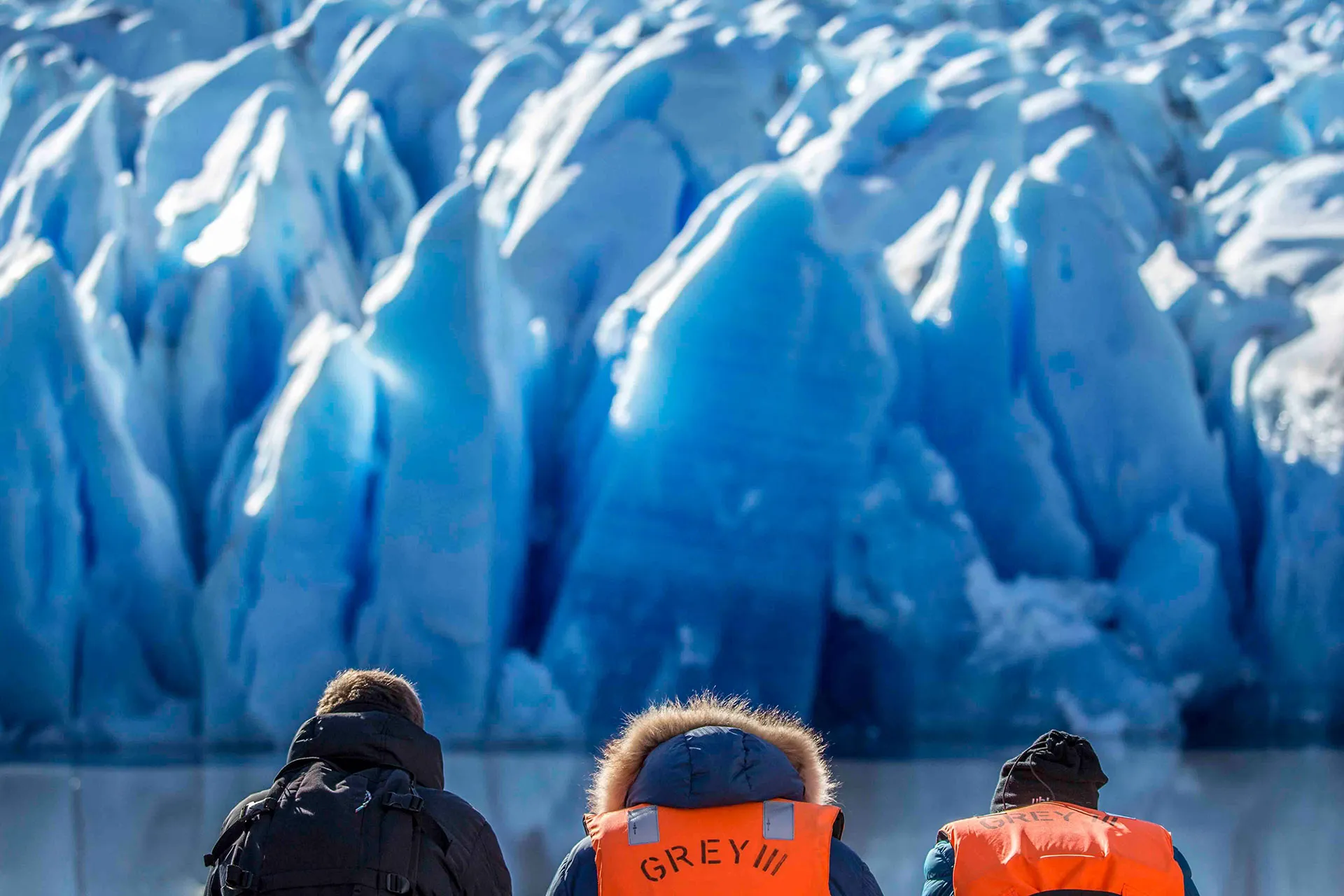 Drei Personen vor riesigem Gletscher