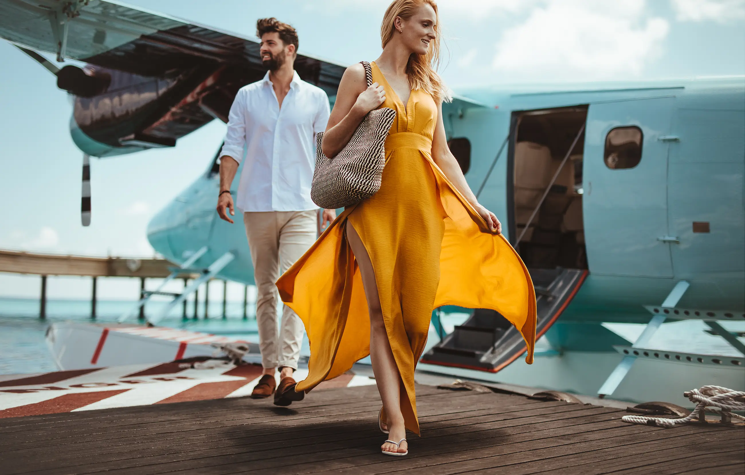 Paar steigt aus Wasserflugzeug an Holzsteg vor Luxushotel auf den Malediven