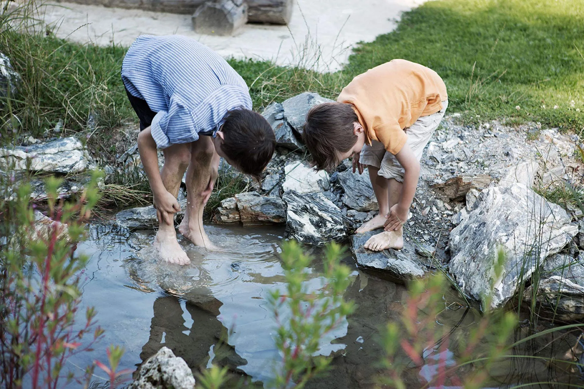 Kinder waschen sich die Füsse in Teich