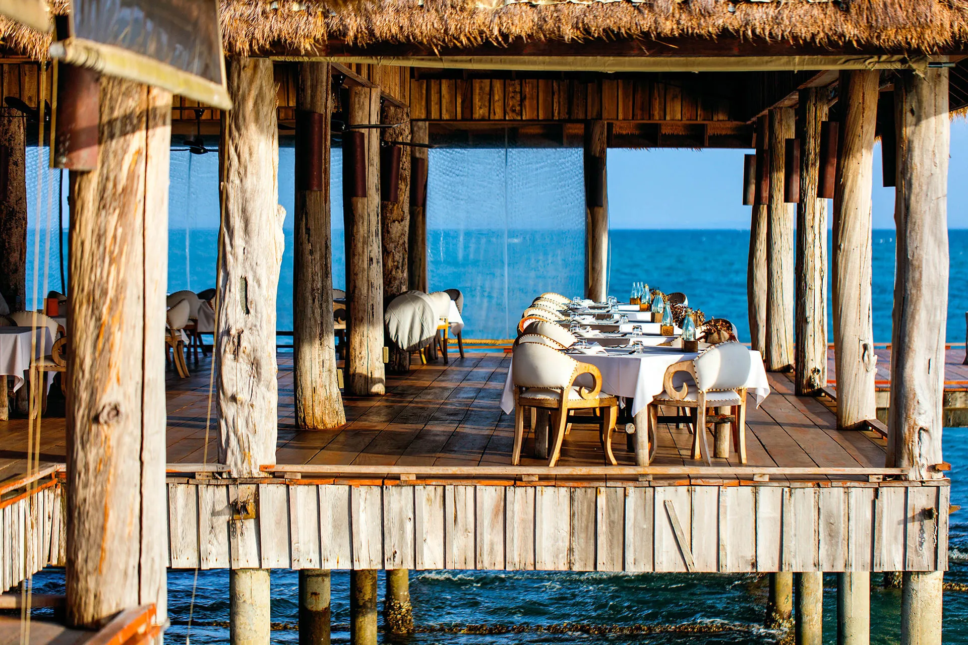 Tische in überdachtem Restaurant über Meer