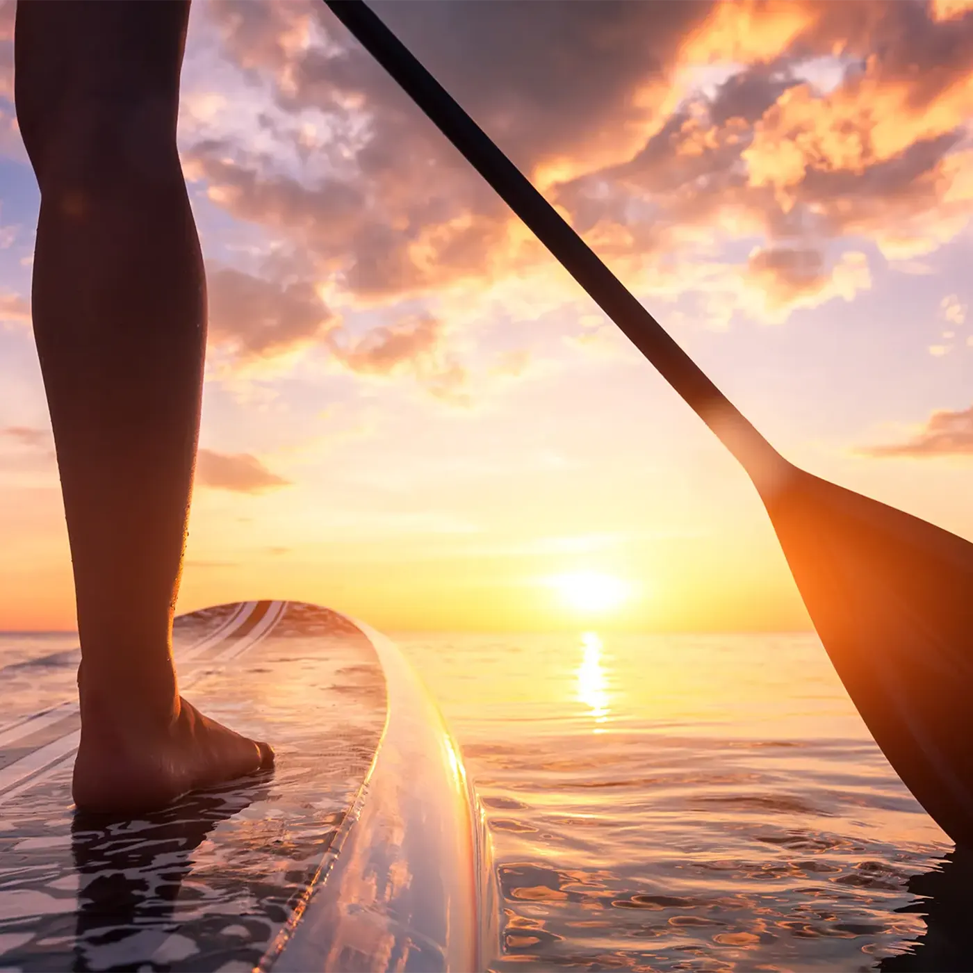 Person auf Paddleboard vor Sonnenuntergang