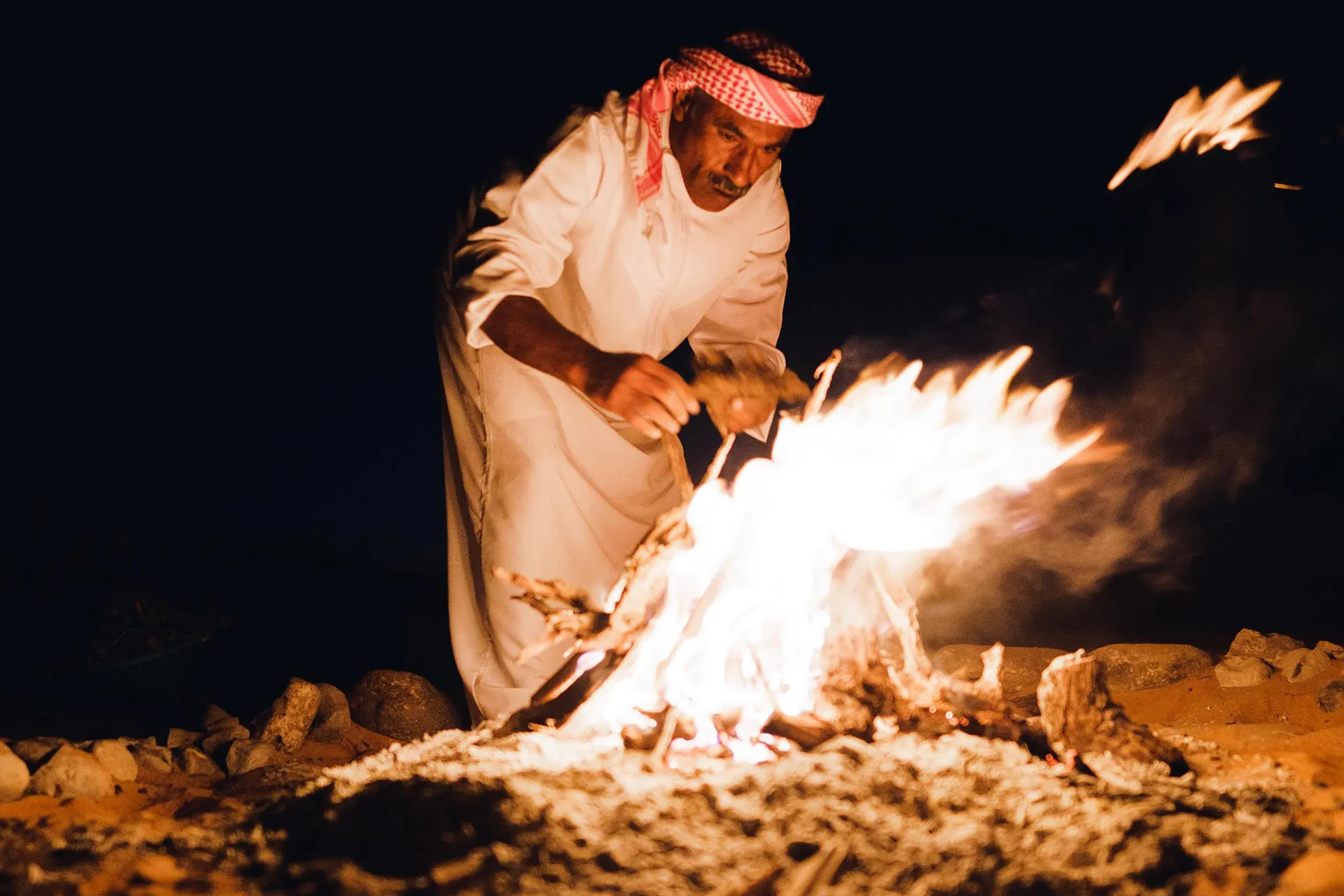 Beduine schürt ein Feuer bei Nacht