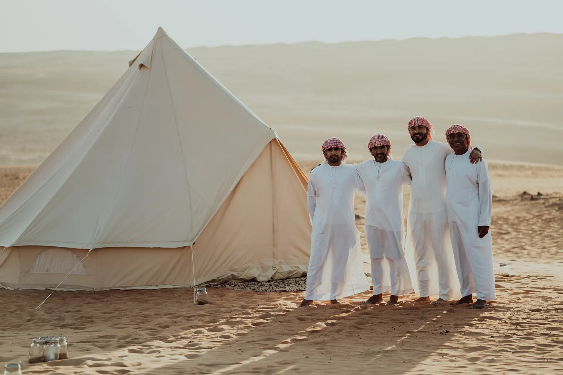 Vier Beduinen neben einem Wüstenzelt