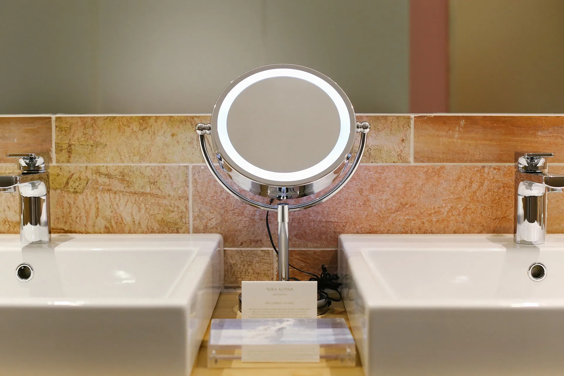 Beleuchteter Kosmetikspiegel zwischen Waschbecken