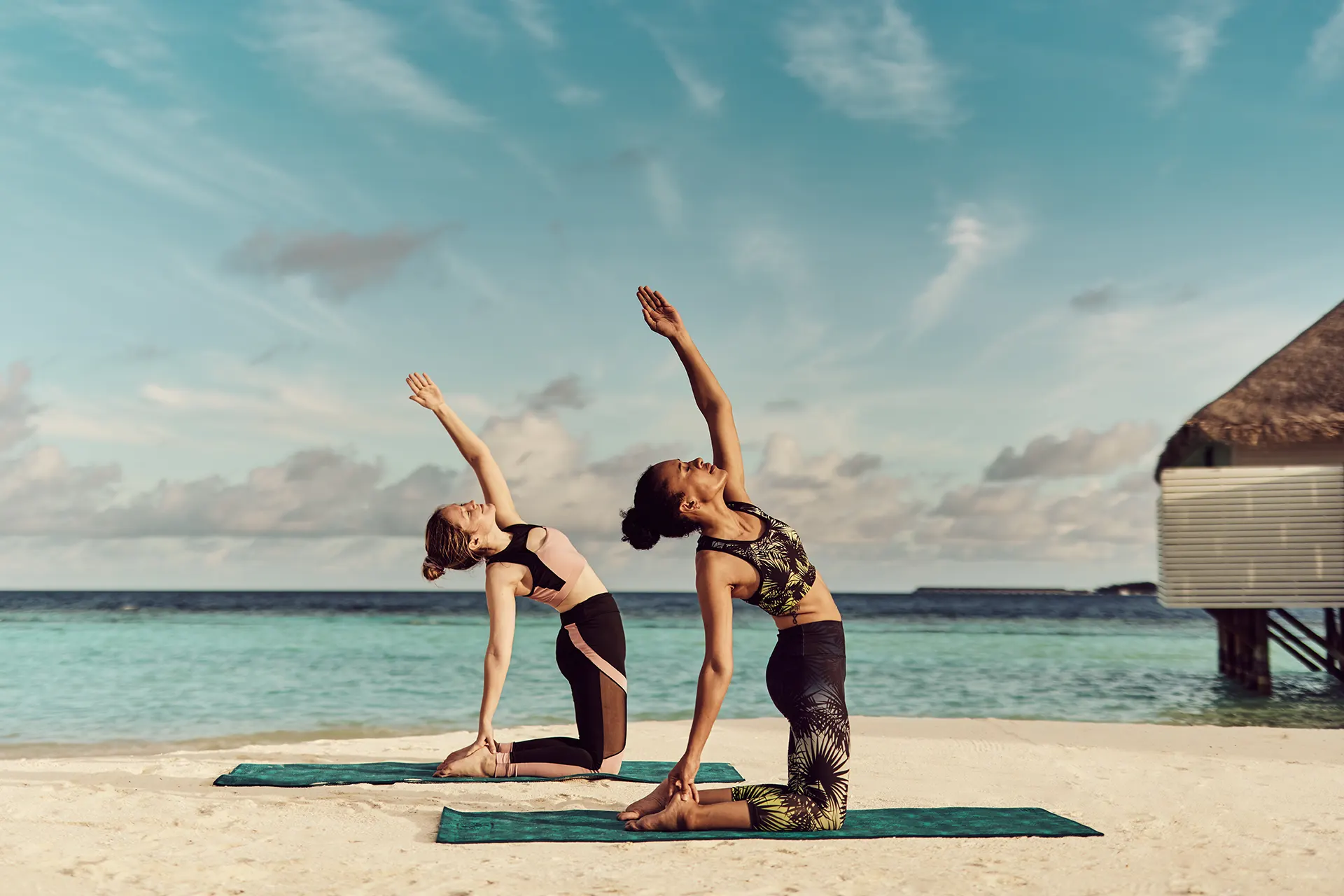 Zwei Frauen machen Yoga am Strand