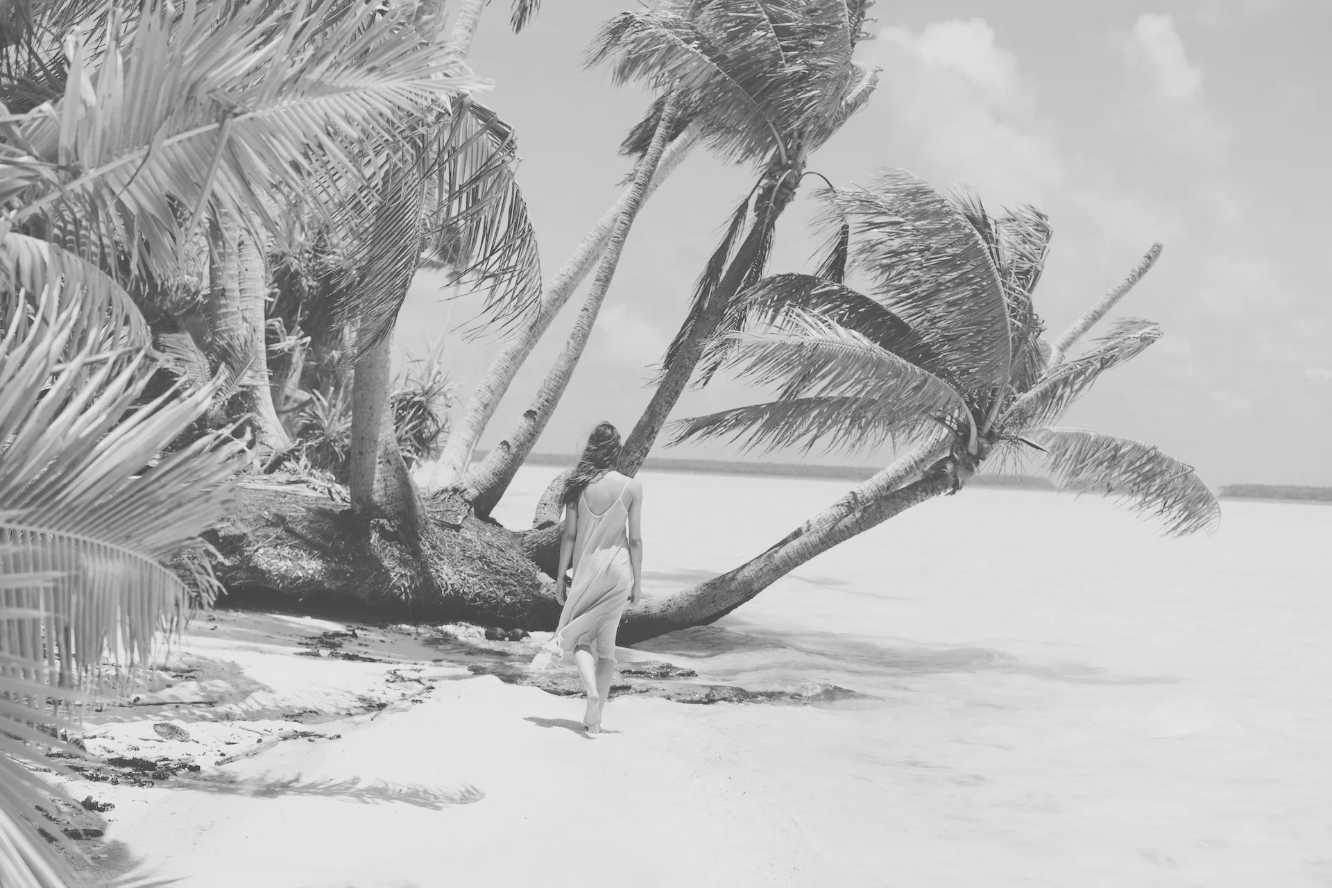 Frau geht an Strand mit Palmen